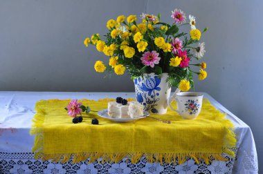 Bir fincan çay ve bir buket sarı çiçekle sakin bir hayat