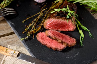 kıyılmış nadir barbekü biftek siyah angus bezelye filiz kekik biberiye baharat ile siyah dikdörtgen plaka üzerinde