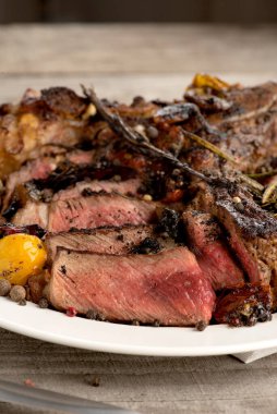 Gri ahşap arka planda nadir biftek mangalında yuvarlak tabak baharatları.