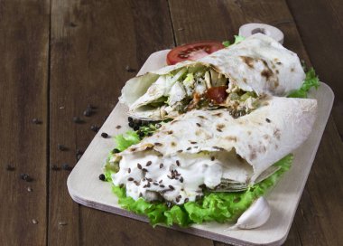 Shaurma, kesilmiş yarısında, bir eski ahşap rustik arka plan üzerinde domates ve biber ile ahşap bir gemide bir ekmek pasta sebzeli et