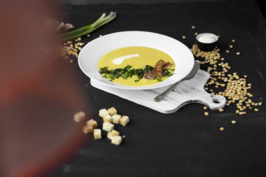 Bezelye çorbası domuz pastırması, maydanoz ve soğan bir kase parçaları ile bir 