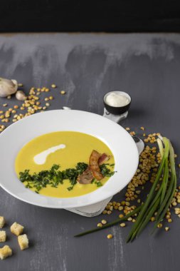 Bezelye çorbası domuz pastırması, maydanoz ve soğan bir kase parçaları ile bir 