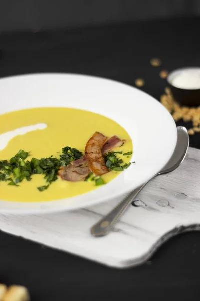 Zuppa di piselli con pezzi di pancetta, prezzemolo e cipolla in una ciotola su un — Foto Stock