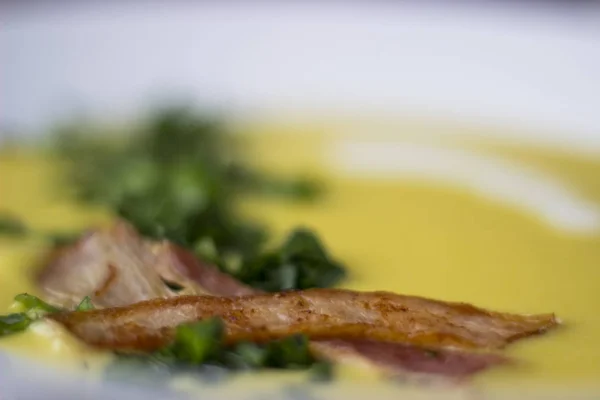 Sopa de ervilha com pedaços de bacon, salsa e cebola em uma tigela em um — Fotografia de Stock