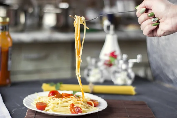 Spaghetti pasta in tomato sauce with cheese and parsley, woman\'s hand.