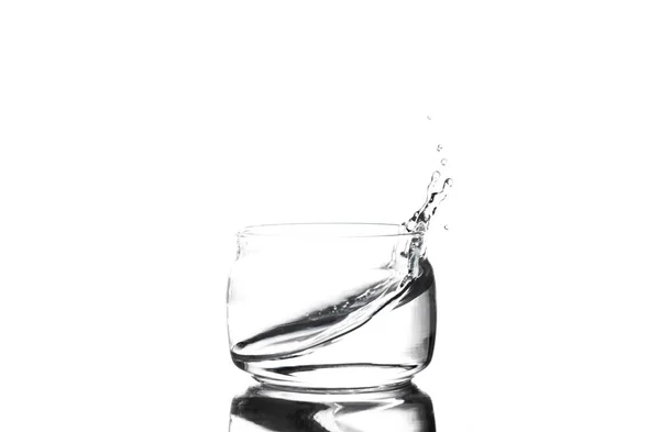 Plusk wody w filiżance szkła na białym tle — Zdjęcie stockowe