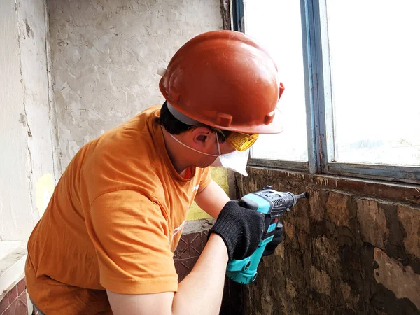 A man with a hammer drill in his hands. Worker with hammer breaking interior wall plastering