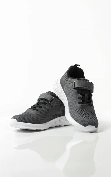 Beyaz arka planda gri çocuk spor ayakkabıları