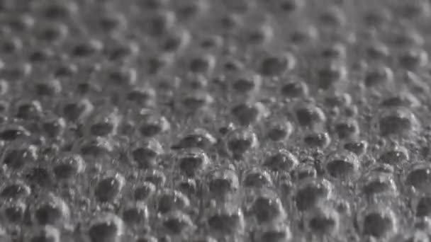 Bubbles of water boiling and evaporating in a black pan. Close up — Stock Video