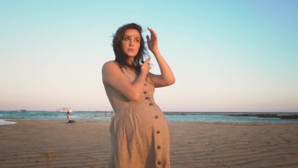Morena grávida alegre mulher andando sozinha em uma praia de areia ao pôr do sol — Vídeo de Stock