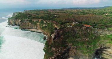 Uluwatu tapınağının havadan üst görünümü, Bali. Kayalar, kayalıklar, büyük dalgalar. Adanın en ünlü turistik yeri. 4k