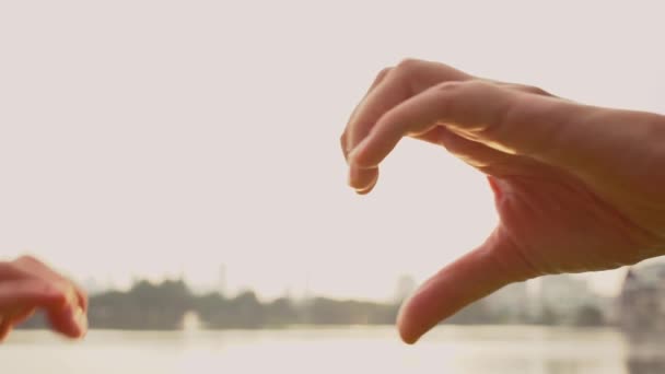 Mère et enfant en forme de cœur avec les mains au coucher du soleil. geste de symbole d'amour avec fusée de soleil orange — Video