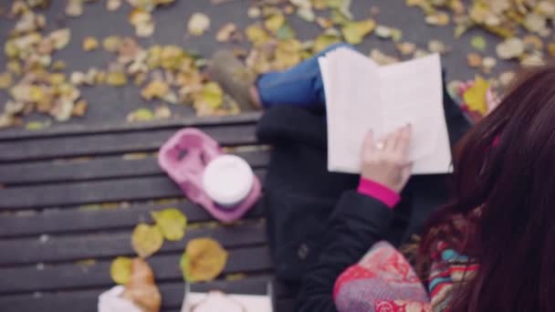 Jonge vrouw lezen boek op Bench in herfst Park met koffie — Stockvideo