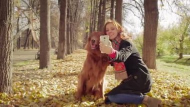 Mutlu çekici kız sonbahar parkta köpek setter ile selfie yapar
