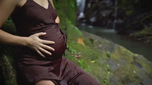 Die schöne schwangere Frau spürt Wehen und konzentriert sich nach dem Schwimmen im Fluss im tropischen Dschungel auf ihre Atmung. Zeitlupe. — Stockvideo
