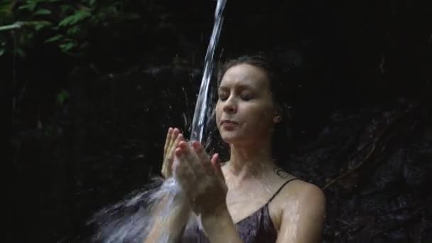 Avslappnad gravid kvinna njuter hälla vatten från en källa i djungeln. Slow motion. — Stockvideo