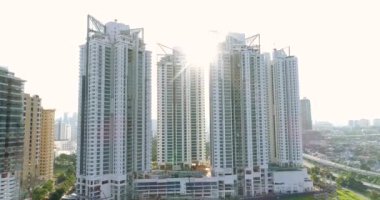 Kuala Lumpur'da yapımı devam eden yeni yüksek katlı konutbinalarının havadan çekilmiş fotoğrafı. Güneş ışınları evlerin arasında parlak parlar. 4k