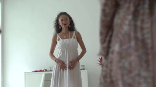 Jolie fille asiatique en robe blanche avec de longs cheveux noirs bouclés dansant pendant la pratique spirituelle féminine — Video