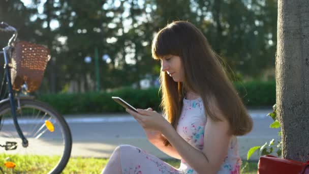 Mujer bonita usando tableta PC en el parque, la lectura de los medios sociales de alimentación, disfrutando del verano — Vídeos de Stock