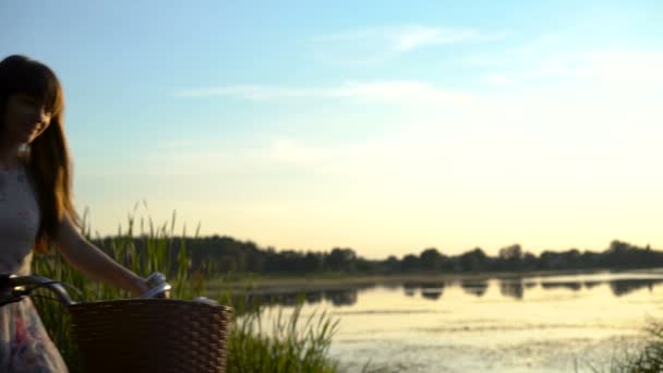 Joven mujer feliz montar en bicicleta junto al lago, disfrutando de la puesta del sol, estilo de vida saludable — Vídeo de stock