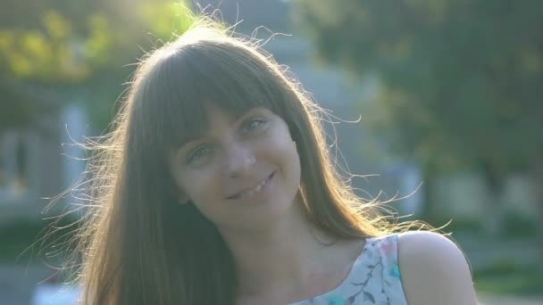 Jovem mulher feliz sorrindo para câmera, vento acenando seu cabelo, verão, slow-mo — Vídeo de Stock