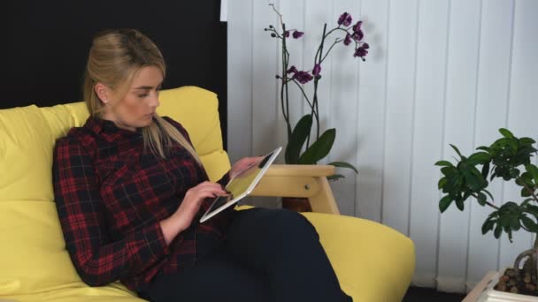 Молодая женщина, используя планшет, прокручивая страницы, просматривая социальные сети дома — стоковое видео