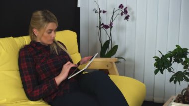 Tablet bilgisayar kullanan genç sarışın kadın, sayfaları kaydırıyor, internetten resimlere bakıyor.