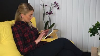 Genç, güzel bir kadın yazı yazıyor, tablet bilgisayarda mesajlaşıyor, arkadaşlarıyla iletişim kuruyor.