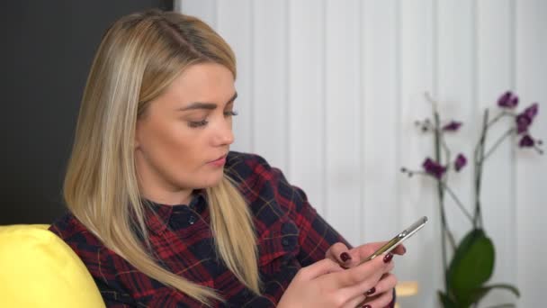 Młoda ładna kobieta smsuje na smartfonie w domu, gadżety, media społecznościowe — Wideo stockowe