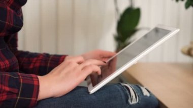 Kadın tablet bilgisayarında sayfaları kaydırıyor, sosyal medyada geziniyor, elleri yakın plan