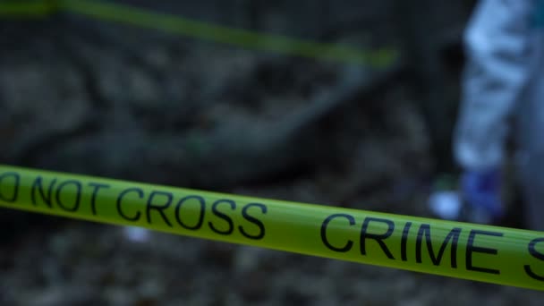 Primer plano de la cinta amarilla de la escena del crimen en el bosque, experto forense trabajando en el sitio — Vídeos de Stock