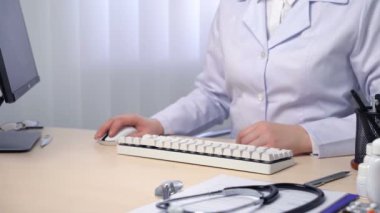 Ofisinde çalışan, klavyede yazan, tıbbi kayıtları tutan kadın doktor