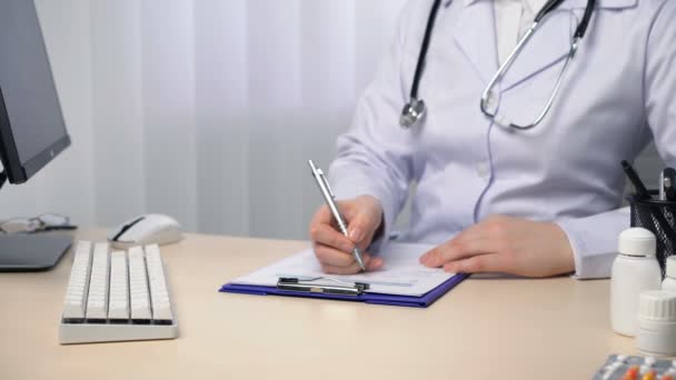 Жінка-лікар пише звіт, робить нотатки, заповнює документи на посаді — стокове відео