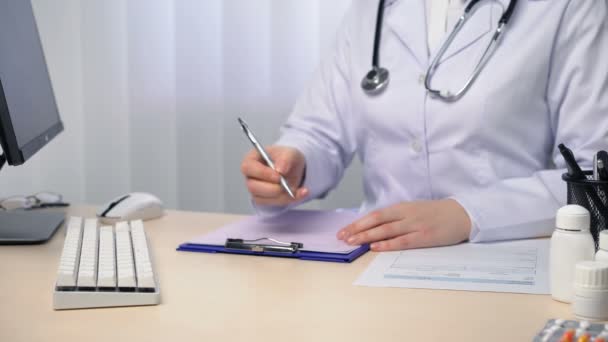 Médico escrevendo diagnóstico, tomando notas, preenchendo formulários no escritório — Vídeo de Stock