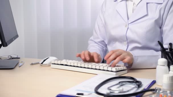 Γιατρός που δακτυλογραφεί μια αναφορά, ελέγχει την ακτινογραφία του ασθενούς, κρατώντας ιατρικά αρχεία — Αρχείο Βίντεο