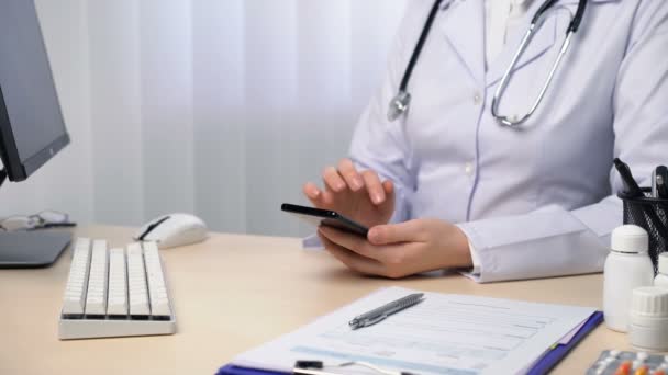 Охорона здоров'я та медичні додатки, лікар використовує смартфон, ковзає, друкує, прокручує — стокове відео