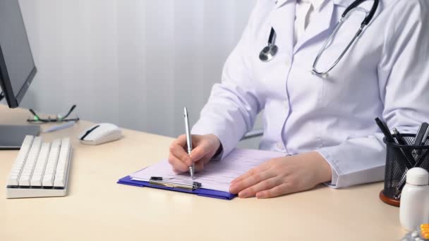 Médico o pediatra que escribe un informe, rellenando documentos en su consultorio — Vídeo de stock