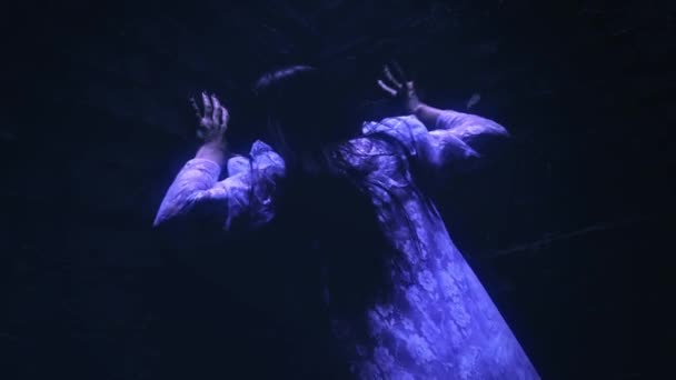 Страшная девушка-зомби, взбирающаяся на кирпичную стену в темноте, призрак убегает из подземного мира. — стоковое видео