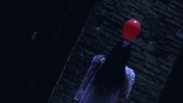Psychotic bride standing with red balloon in dark building, luring to danger — Stock Video