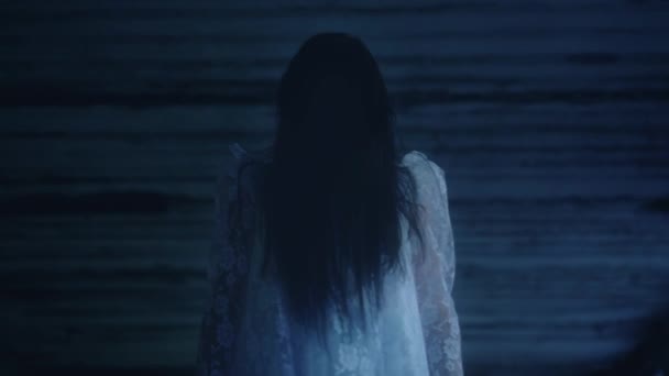 Таинственное существо в белом платье, стоящее на ветру, лицо покрыто волосами, страх — стоковое видео