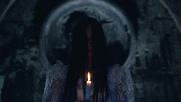 Mystic female standing in gothic church with burning candle, possessed by demon — Stock Video