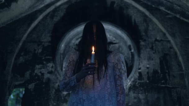 Bruxa minosa com vela acesa perto da cripta de pedra, ritual de magia negra — Vídeo de Stock