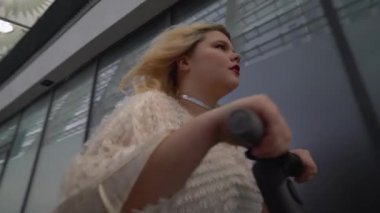 Elektrikli scooter kullanan kendine güvenen genç bir kadın, aktif şehir hayatı, özgürlük.