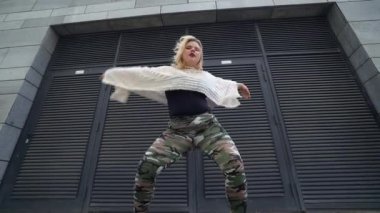 Kendine güveni tam şişman bir kadın açık havada müzik yapıyor, sokak dansı yapıyor, vücut pozitifliği var.