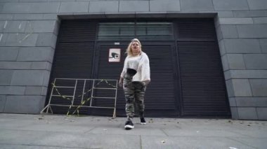 Şehir sokağında hip-hop dansı yapan aktif beden ölçülerinde bir kız.