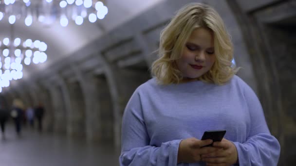 Красивая молодая женщина прокручивает смартфон в метро, используя транспортное приложение — стоковое видео