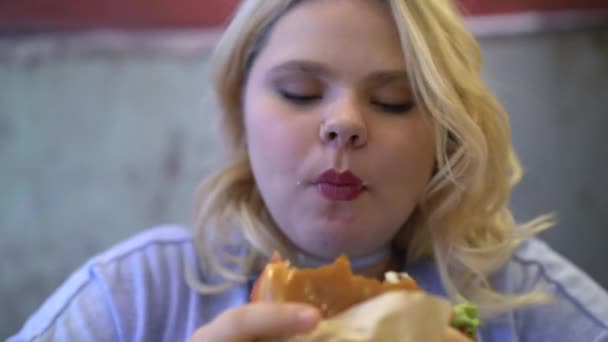 Mujer gorda comiendo hamburguesa grasosa y papas fritas, adicción a la comida rápida, obesidad — Vídeos de Stock