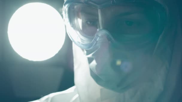 Laboratorium expert in beschermende uitrusting kijken naar bloed monster buis, infectie gevaar — Stockvideo