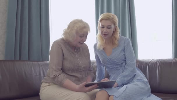 Madre e figlia anziana che guardano le foto su tablet, app di shopping online — Video Stock