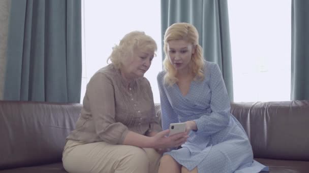 Blonde Frau lehrt Mutter Smartphone-Anwendung, moderne Technologie — Stockvideo